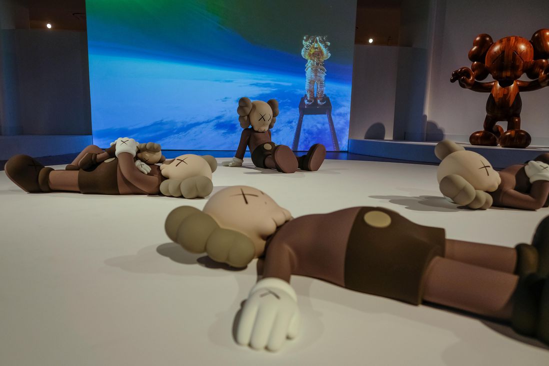 Sculptures of figures on the floor. Inside the KAWS exhibit at Brooklyn Museum